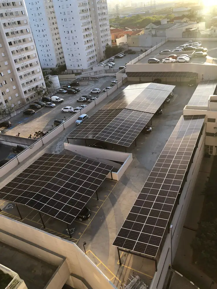 Carport solar sobre estacionamento de condomínio ao pôr do sol